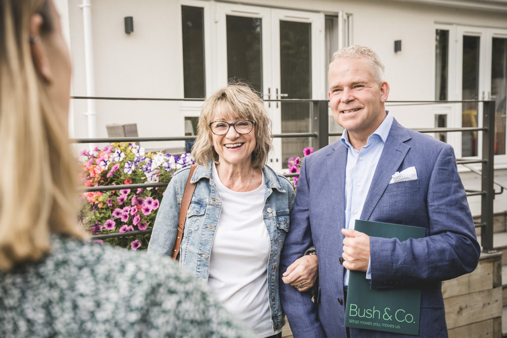 Bush and Co property Sales estate agent showing a couple a property in a garden with stunning flowerbed