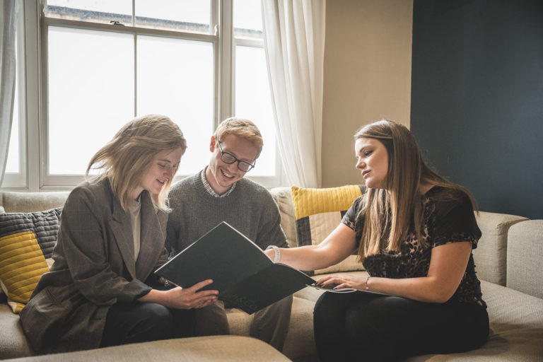 Bush and Co property Lettings estate agent talking to a couple about their options in letting a property with Bush and co. in a living room on a couch